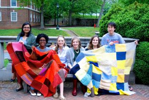 Warm Up America students posing on Grounds with quilt