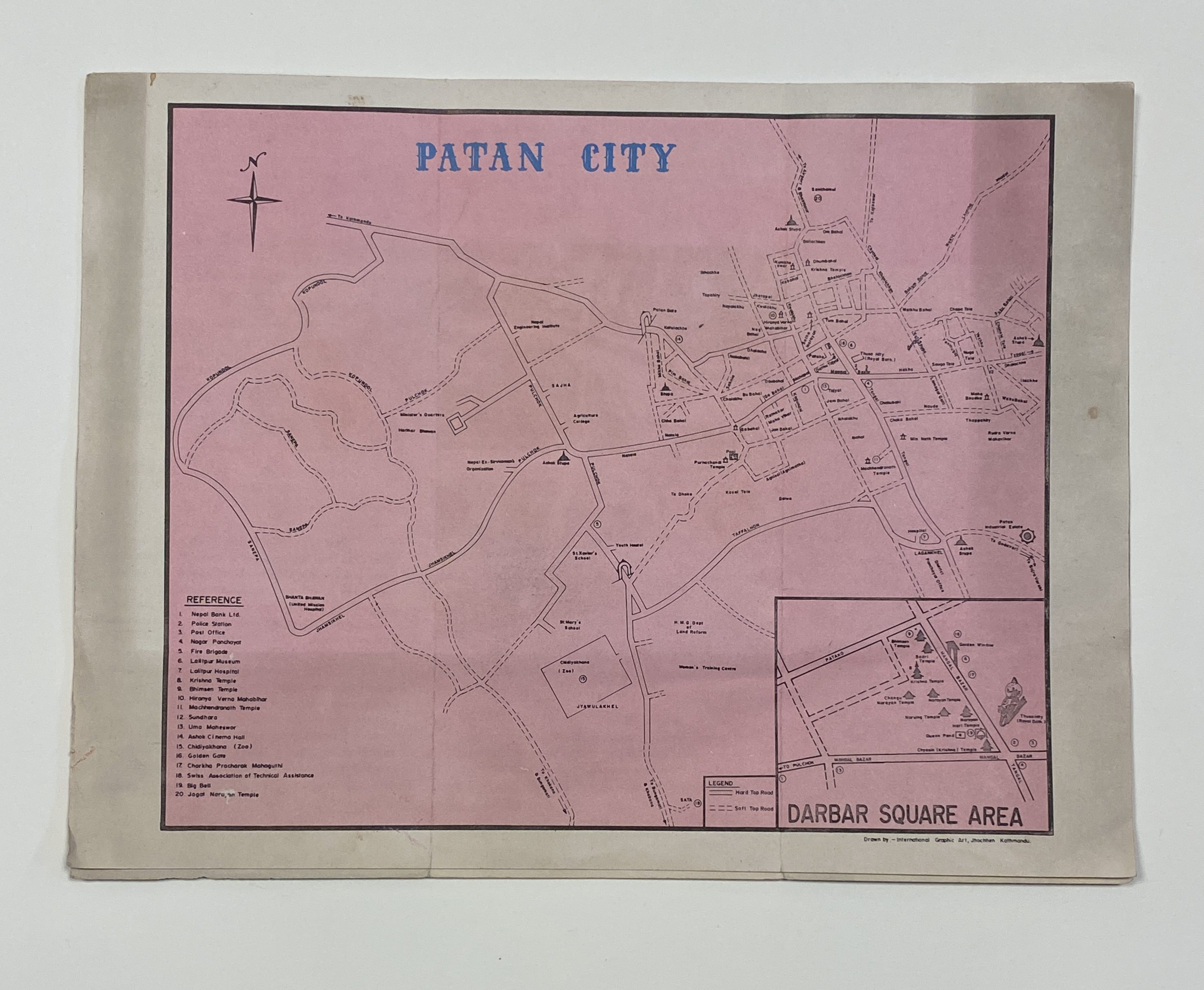 A single sheet of white paper with a printed street map in English in black ink on a pink background, with the title "Patan City" in bright blue ink.
